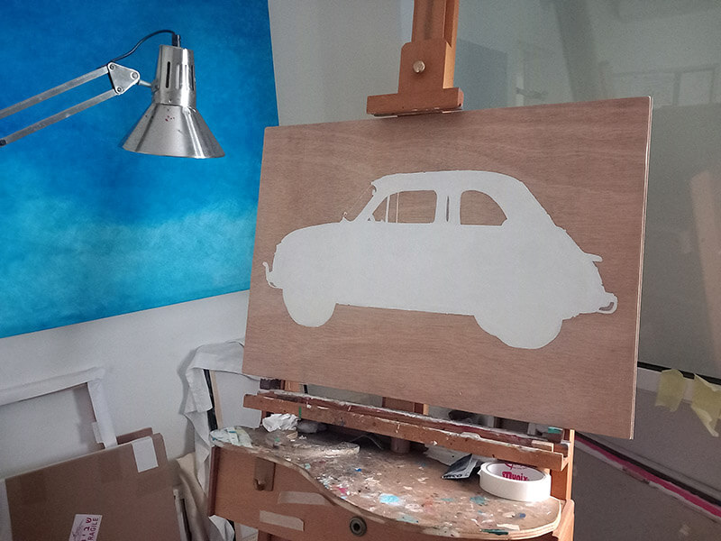 Outline shape of Fiat 500 filled in with white paint. On an easel in artist's studio.