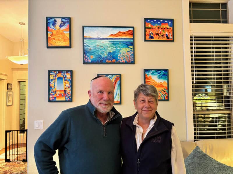 Biblical art for the Home : A mature couple in front of their brightly-coloured Biblical art collection. Collecting Biblical Art
