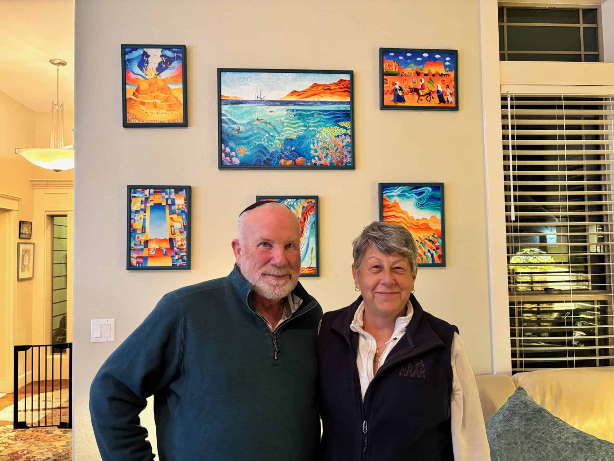 Biblical art for the Home : A mature couple in front of their brightly-coloured Biblical art collection. Collecting Biblical Art
